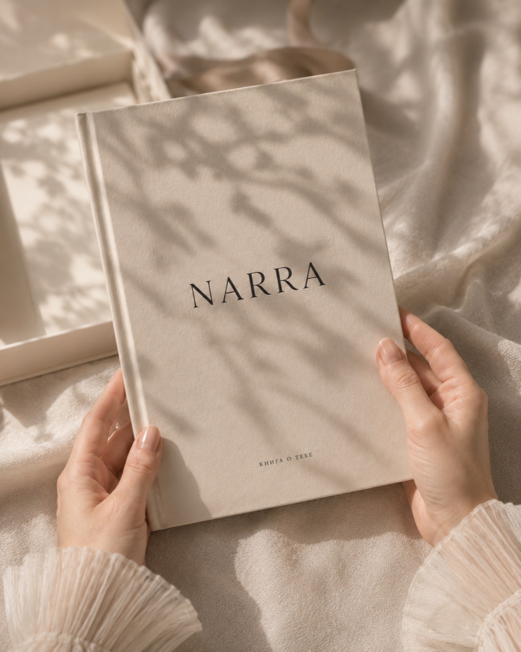 Книга NARRA в руках в мягком свете